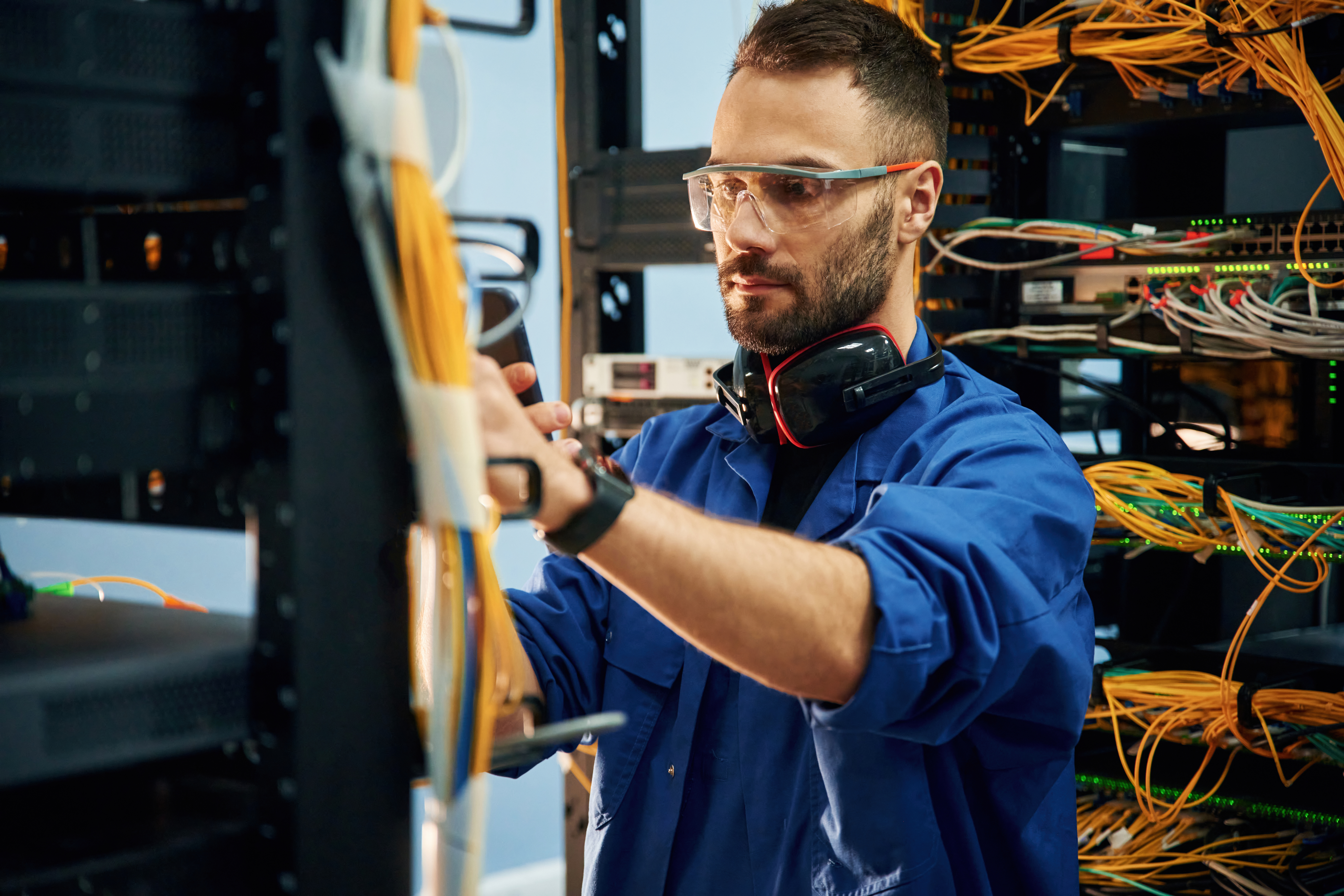 Restoring the internet connection. Young man is working with equipment and wires in server room.